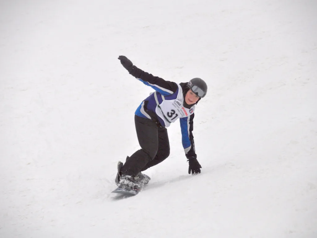 Snowboarder in tiefer Hocke auf der Piste.